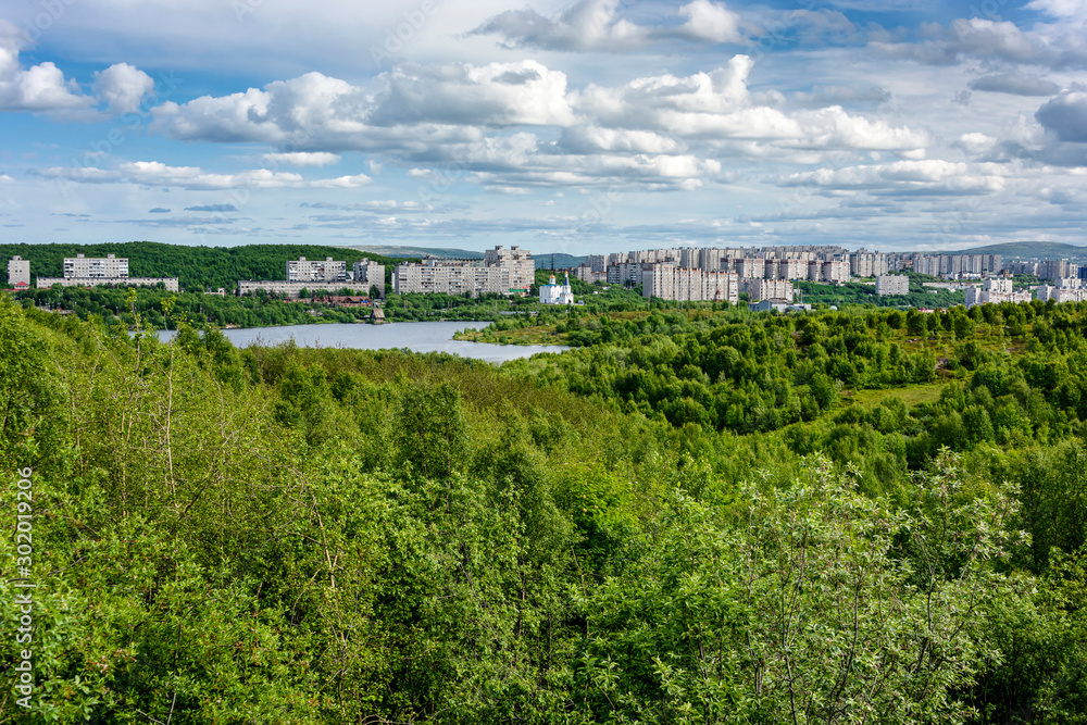 Russia, Barents Sea, Murmansk: Skyline panorama view of the northern Russian town with Lake Semyonovskoye, new concrete buildings, green trees and blue sky in the background - travel destination