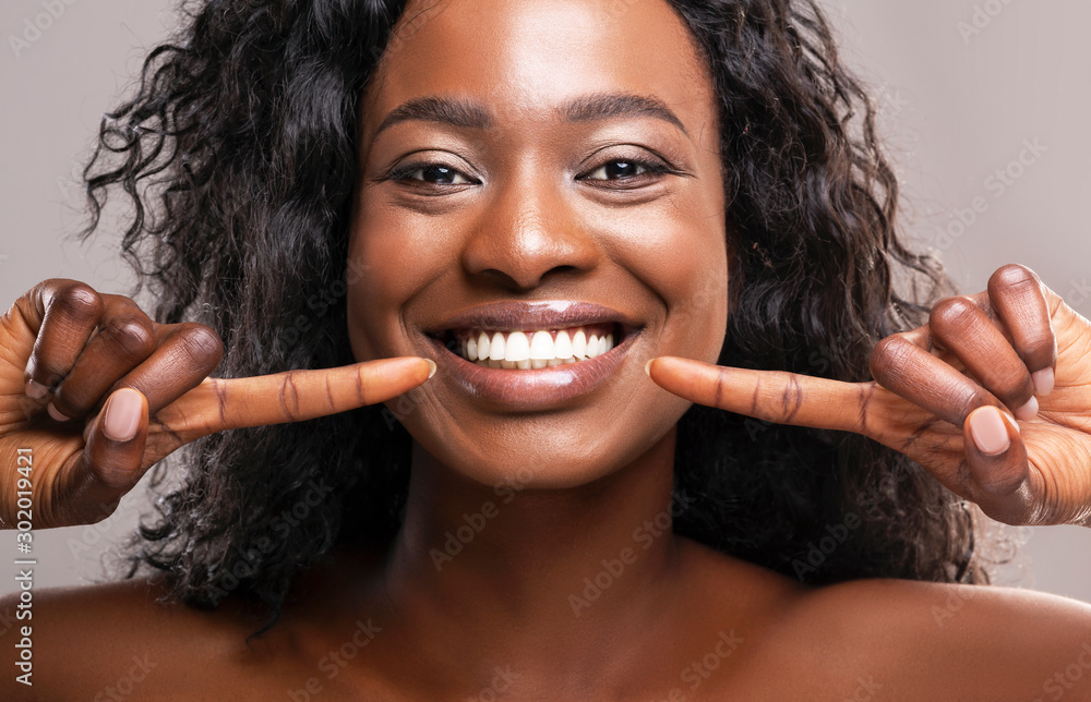 © Prostock-studio - Happy black woman pointing at her perfect white teeth