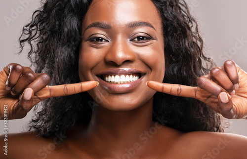Happy black woman pointing at her perfect white teeth