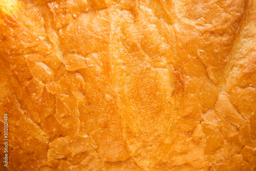 The texture of the crust of bread. Tasty fresh bread, close up. Macro of a french loaf showing the texture of the crust baked brown and golden. Flat lay. Food concept. A place for your inscription.