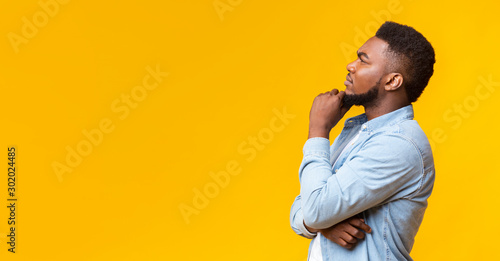 Fototapeta Young african american guy thinking about something over yellow background
