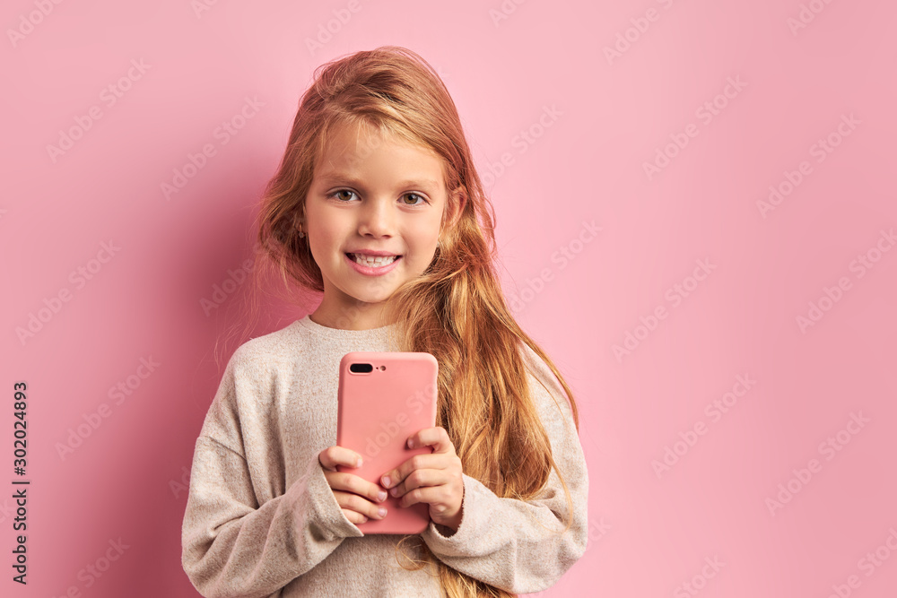 Open-minded girl in white blouse using smartphone isolated over pink background. Modern technologies nowadays, digital device concept Open-minded girl in white blouse using smartphone isolated over pink background. Modern technologies nowadays, digital device concept