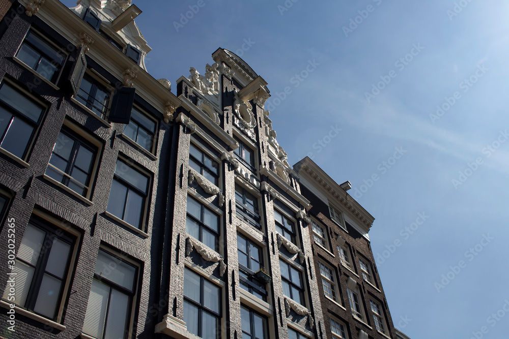 Bottom view of historical, traditional and typical buildings showing Dutch architectural style in Amsterdam. It is a sunny summer day.