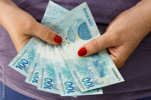 Brazilian monet, reais banknotes in a woman's hand