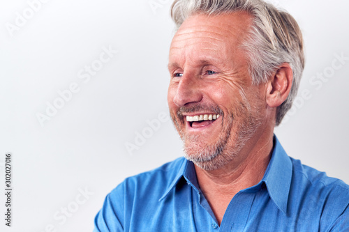 Studio Shot Of Mature Man Against White Background Laughing At Camera