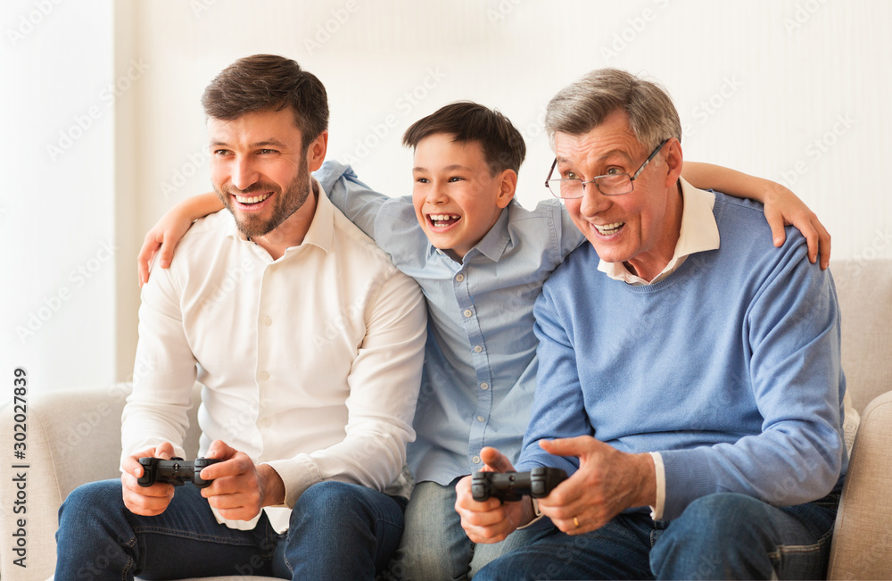 Elderly Man, Mature Son And Grandson Playing Videogame At Home Elderly Man, Mature Son And Grandson Playing Videogame At Home