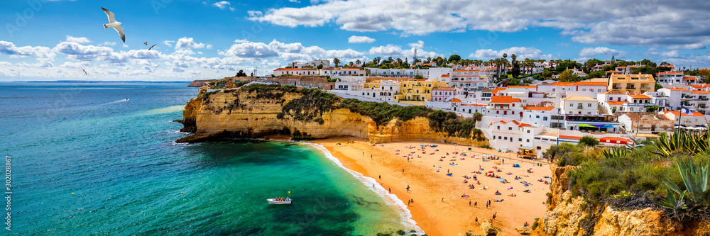 Fototapeta Widok Carvoeiro wioska rybacka z piękną plażą, Algarve, Portugalia. Widok plaża w Carvoeiro miasteczku z kolorowymi domami na wybrzeżu Portugalia. Wieś Carvoeiro w Algarve w Portugalii.
