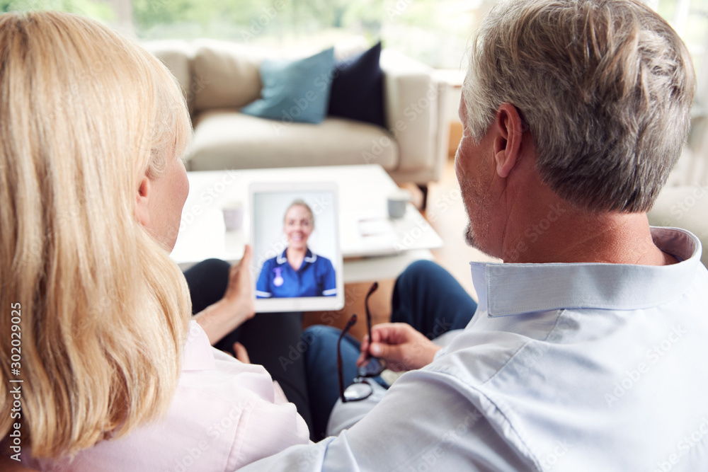 Obraz premium Mature Couple Having Online Consultation With Female Nurse At Home On Digital Tablet
