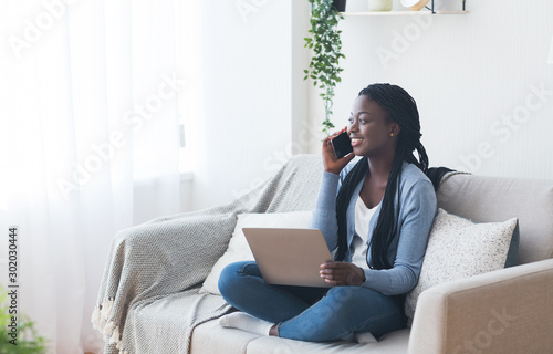 Woman talking on phone and using laptop, searching job online