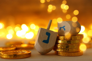 religion concept of of jewish holiday Hanukkah with wooden dreidels (spinning top) and chocolate coins over wooden table and bokeh lights background