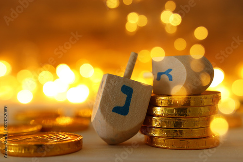 religion concept of of jewish holiday Hanukkah with wooden dreidels (spinning top) and chocolate coins over wooden table and bokeh lights background photo