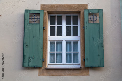 Ancient colorful window with open wooden shutters on wall of house