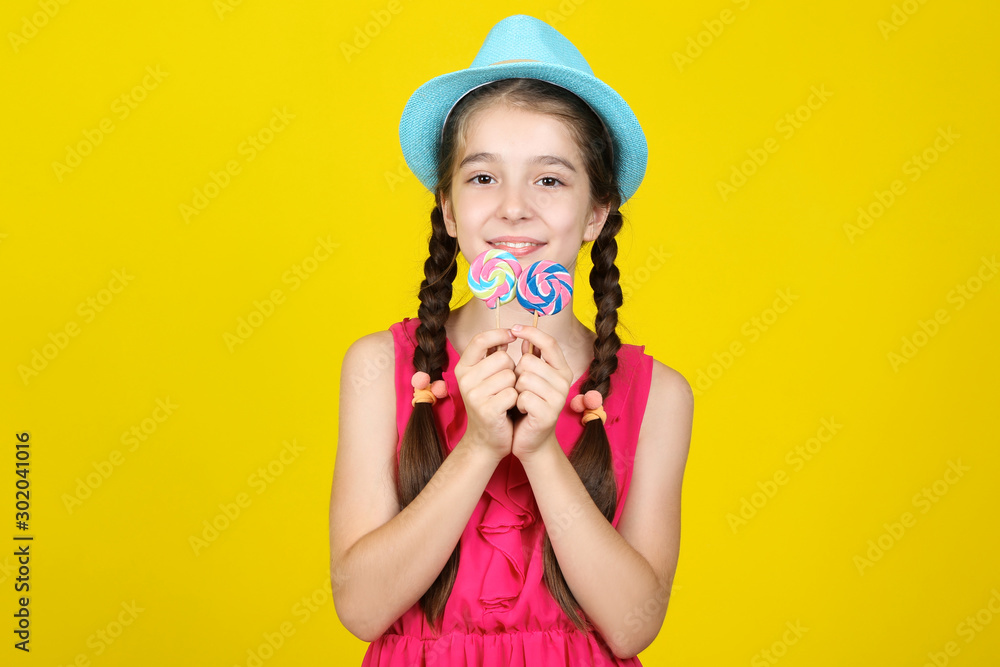 Beautiful young girl with sweet lollipops on yellow background