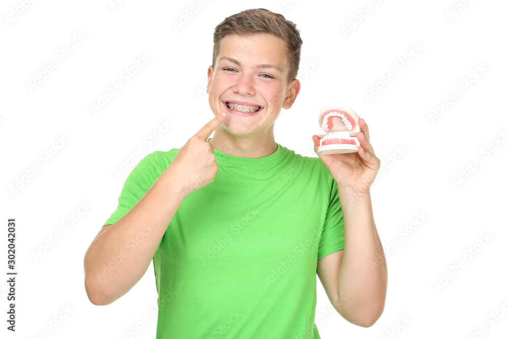 Young man with dental braces holding teeth model on white background Young man with dental braces holding teeth model on white background