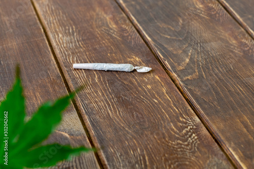 Cannabis (marijuana) joint on wooden table with