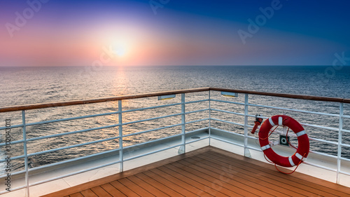 Fotografiet Beautiful scenic sunset view from the deck of a cruise ship with safety railing in the foreground