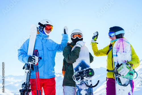 Photo of three athletes in helmet doing handshake at snow resort.