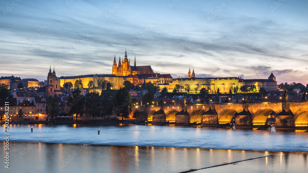 Prague Castle and the Charles Bridge at sunset in Prague, Czech Republic, Vltava river in foreground