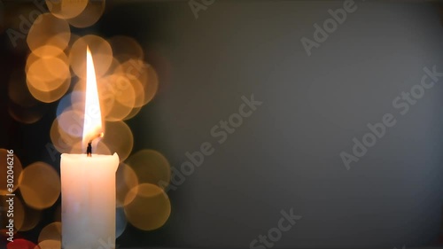 Burning Christmas candle with blinking light bokeh and copy space in the background photo