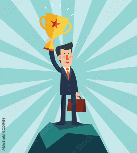 Successful, smiling, young, happy businessman standing on a top of a mountain and holding up winning trophy