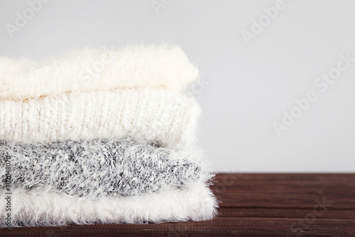 Folded knitted sweaters on grey background