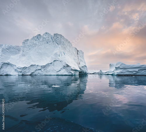 Arctic nature landscape with icebergs in Greenland icefjord with midnight sun sunset sunrise in the horizon. Early morning summer alpenglow during midnight season. Ilulissat, West Greenland. © Mathias