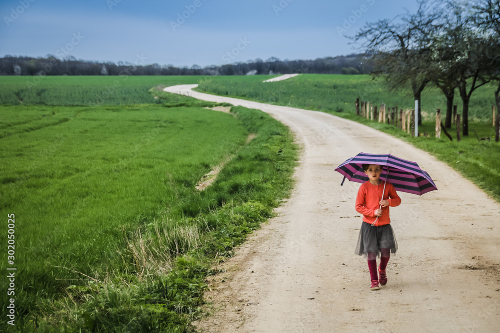 Obraz premium petite fille avec un parapluie sur un chemin