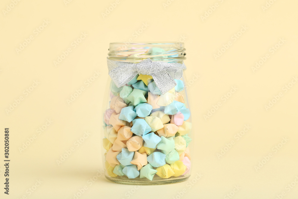 Colorful paper stars in glass jar on beige background Colorful paper stars in glass jar on beige background