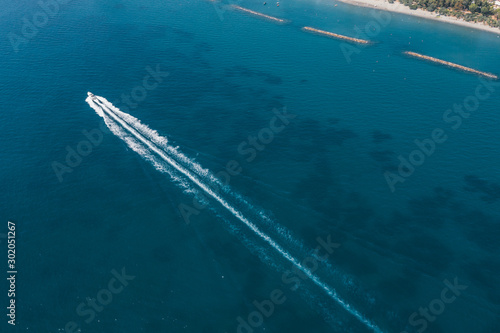 Aerial view of jet ski cruising at high speed on emerald sea water