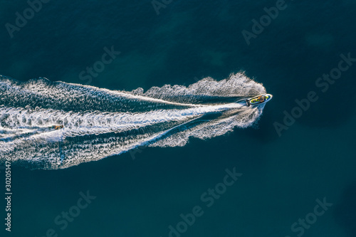 Jet ski rides a wakeboarding in the blue sea. Aerial view © Viachaslau