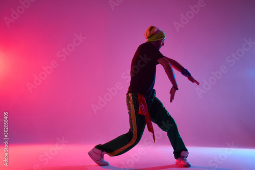 Obraz na plátně Handsome young professional hip hop dancer performing on stage of dance school,