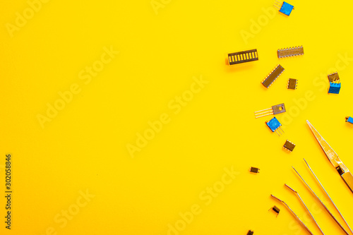 Tweezers and electronic parts on a yellow background