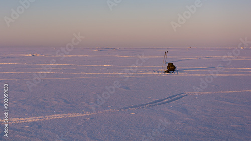Winter hiking on the sea ice with sled full of equipment and ski poles