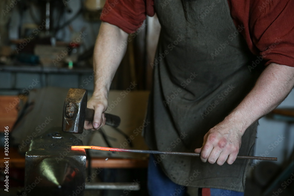 blacksmith knocks a hammer on the hot metal on the anvil. the work of a blacksmith in the forge blacksmith knocks a hammer on the hot metal on the anvil. the work of a blacksmith in the forge