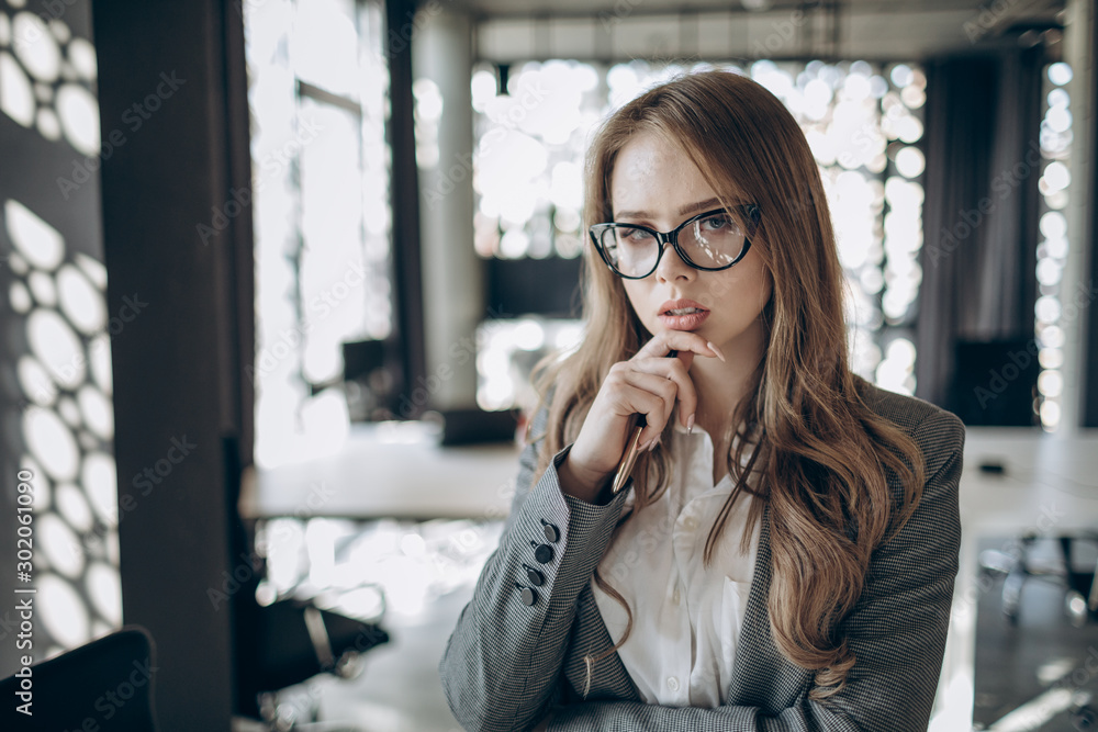 Portrait of young cute thoughtful female office clerk in glasses Portrait of young cute thoughtful female office clerk in glasses