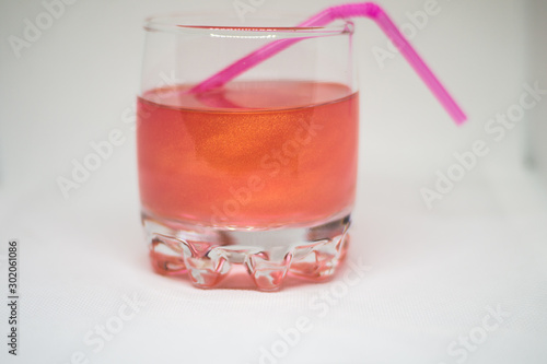 Pink drink in a glass cup with a pink straw for cocktails isolated on white background