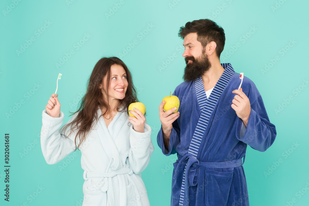 personal care in morning. couple in bathrobe grooming. bearded man and girl healthy smile. family couple hold apple with toothbrush. having healthy and strong teeth. Healthy habits personal care in morning. couple in bathrobe grooming. bearded man and girl healthy smile. family couple hold apple with toothbrush. having healthy and strong teeth. Healthy habits