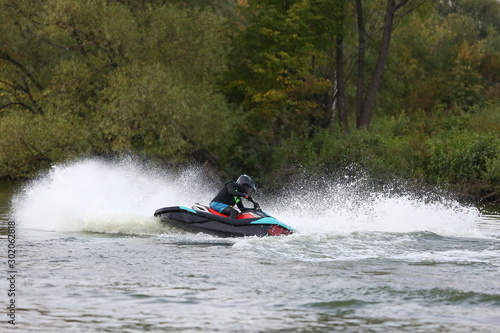 man in a helmet and wetsuit performs tricks on a jet ski. sport riding a personal watercraft. stunt riding on jet ski