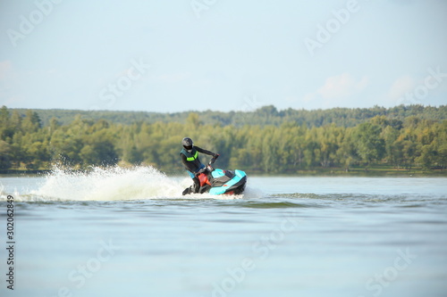 man in a helmet and wetsuit performs tricks on a jet ski. sport riding a personal watercraft. stunt riding on jet ski
