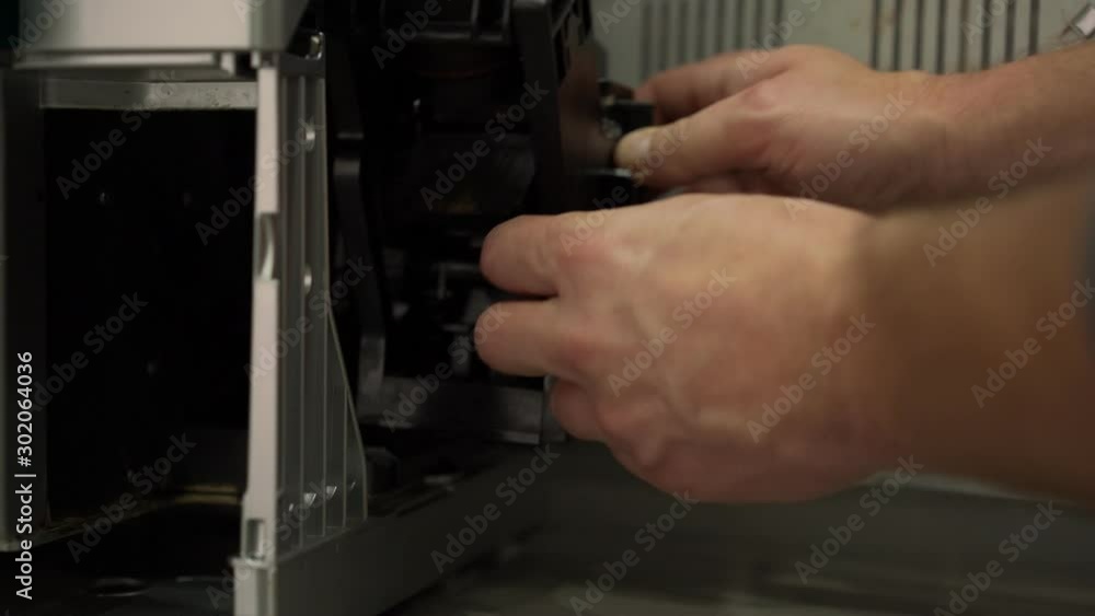 man removes dirty black plastic coffee maker block from stainless steel coffee machine housing close view