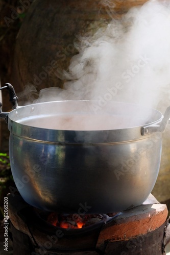 White smoke from a hot cooking pot in old style kitchen area with dark background re