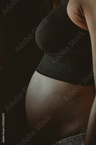 Pregnant woman silhouette over black background. Side view
