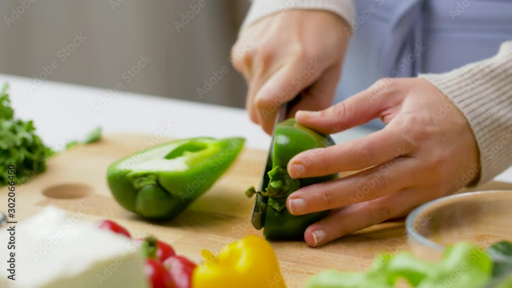 healthy eating, vegetarian food and cooking concept - young woman with kitchen knife cutting pepper in half and removing seeds at home healthy eating, vegetarian food and cooking concept - young woman with kitchen knife cutting pepper in half and removing seeds at home