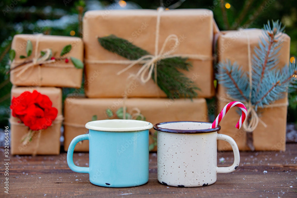 Two cups of coffee with boxes and fairy lights and pine tree on background Two cups of coffee with boxes and fairy lights and pine tree on background