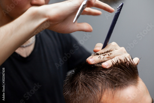 handsome guy get a haircut at the hairdresser, Kazakh hairdresser cuts manually with scissors and a comb, short haircut close-up