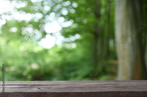  Image of grey wooden table in front of abstract blurred background of trees on a green meadow