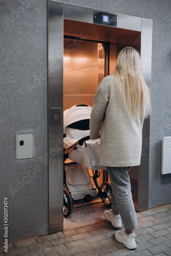 a young woman with a stroller enters the Elevator booth