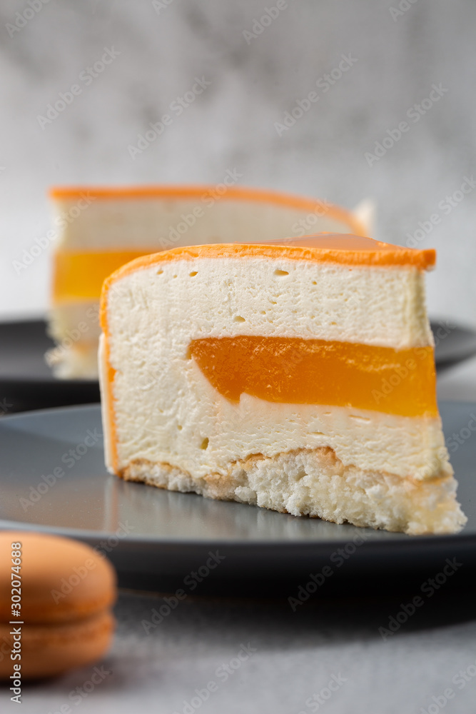 Elegant Cake with coconut, passion fruit, mangoes and bananas, covered with chocolate glaze. Slice of orange layered cake on marble background. Wallpaper for pastry cafe or cafe menu. vertical.
