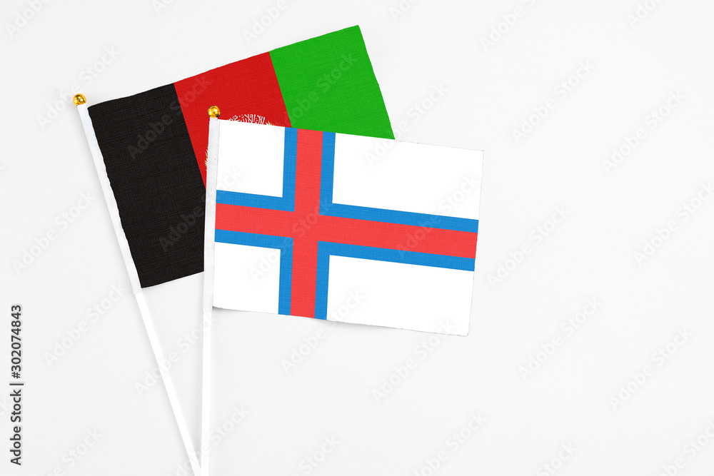 Faroe Islands and Afghanistan stick flags on white background. High quality fabric, miniature national flag. Peaceful global concept.White floor for copy space.
