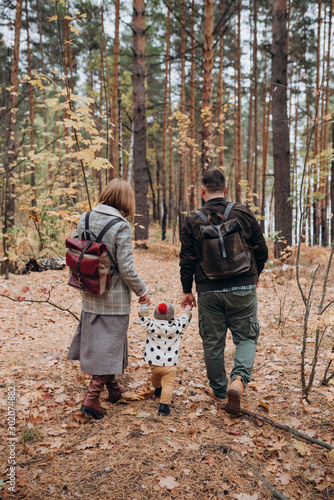 young parents a man and a woman walking in the woods with a child © Евгений Александров